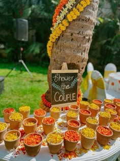 there are many small cups on the table with flowers in them and a sign that says shower the couple