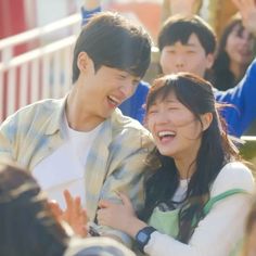 two young people are laughing together in front of an audience, one is holding his arm around the other's shoulder