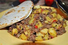 a yellow plate topped with food next to a tortilla