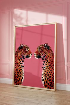 a framed photograph of two leopards facing each other on a pink wall in an empty room