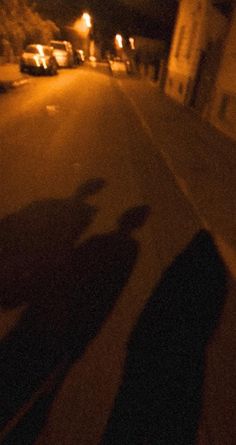 the shadow of a person riding a skateboard on a city street at night time