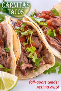 two tacos on a plate with limes and cilantro in the background