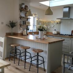 a kitchen island with three stools in front of it and lights hanging from the ceiling