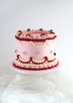 a pink and white cake with hearts on it sitting on a plate in front of a white background