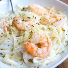 pasta with shrimp and parmesan cheese in a white bowl on a wooden table