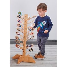 a young boy standing next to a wooden tree