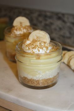 two desserts in glass jars with banana slices on top