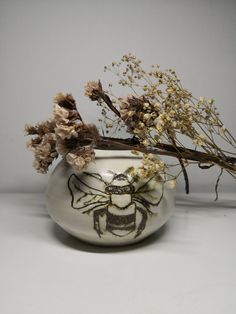 a vase with dried flowers in it sitting on a table next to a white wall