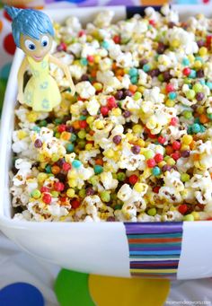 a child's toy is sitting on top of a bowl full of candy popcorn