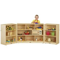 a child standing in front of a bookcase filled with toys