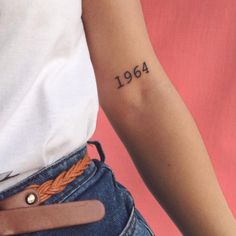 a woman's arm with a tattoo on it that reads, 1994 and has an orange braid