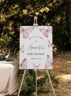 a welcome sign for a baby shower is displayed in front of a table covered with greenery