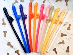 six different colored straws are lined up on a marble surface with dog bones scattered around them