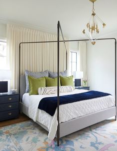 a bedroom with a four poster bed, blue and green pillows, and a chandelier hanging from the ceiling