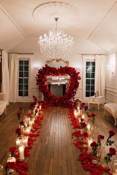 a long table with candles and roses on it in front of a mirror that has a heart shaped frame