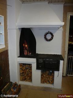 a fireplace with firewood stacked in it and a wreath hanging on the wall next to it