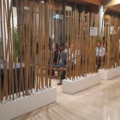 several people are sitting in chairs with wooden poles on the wall and behind them is a display of bamboo sticks