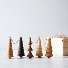 small wooden christmas trees are lined up in a row next to a box on the floor