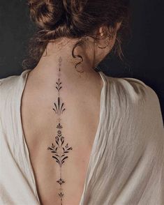 the back of a woman's neck with an intricate tattoo design on her left side