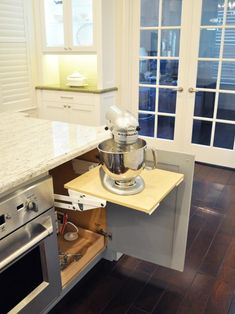 a mixer is sitting in the middle of a kitchen cabinet drawer with an open door