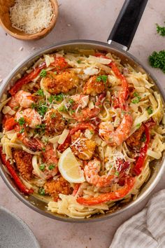 a pan filled with shrimp, pasta and parmesan cheese on top of a table