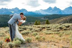 a bride and groom kissing in the mountains