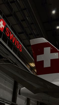 an airplane with the swiss flag on it is parked in a hanger at an airport