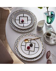 the table is set with plates, cups, and vases on top of it