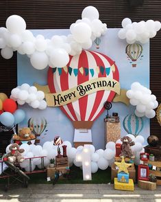 a birthday party with balloons, teddy bears and hot air balloons on the wall behind it