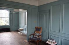 an empty room with blue walls and wooden floors, including a chair in the corner