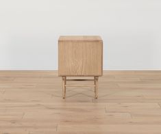 a small wooden box sitting on top of a hard wood floor next to a white wall