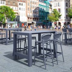 an outdoor dining table and chairs in the middle of a city square with people walking around