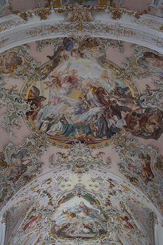 an ornate ceiling with paintings on it in a room filled with pink and white walls