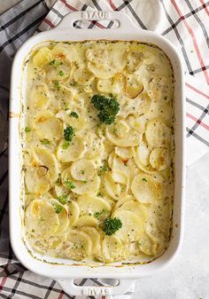 a casserole dish filled with pasta and broccoli on a checkered cloth