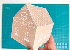 a hand holding up a paper model of a house