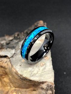 a black and blue ring sitting on top of a piece of wood with the light shining through