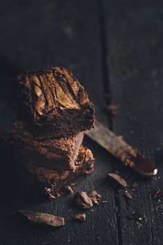 a piece of chocolate cake sitting on top of a wooden table next to a knife