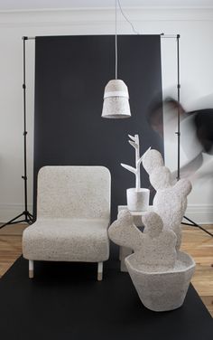 two chairs and a table in front of a black wall with a white lamp hanging from it