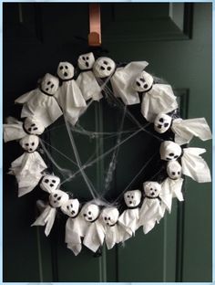 a wreath decorated with fake ghost heads and white paper bats is hanging on the front door