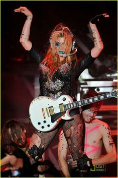 lady in fishnet outfit playing guitar on stage