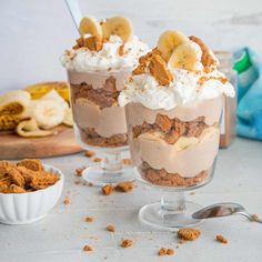 two desserts with banana slices and whipped cream in them on a white counter top