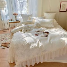 an unmade bed with white linens in a bedroom next to a large window