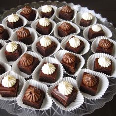 chocolate desserts are arranged in paper cups on a glass platter