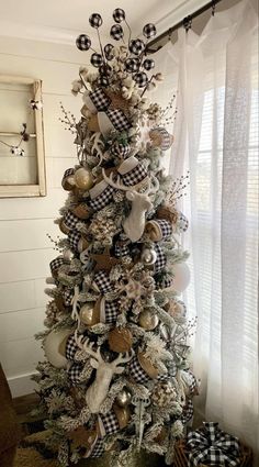 a christmas tree decorated with black and white plaid ribbon, silver ornaments and deer heads