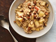 a bowl filled with oatmeal and nuts next to a spoon on a table