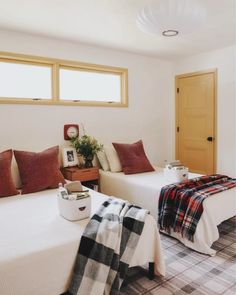 two beds in a room with plaid blankets and pillows on the bed, next to each other