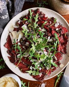 a white plate topped with meat and veggies on top of a wooden table