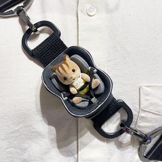 a keychain with a small stuffed animal in it's pocket on top of a white shirt