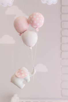 some pink and white balloons are hanging in the air above a crib that is decorated with polka dots