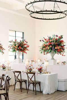 a room with tables, chairs and vases filled with flowers